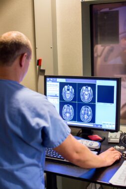 An imaging professional reviewing MRI scan data in front of a monitor