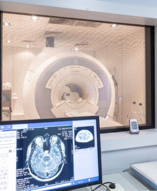 An MRI scanner in the background with a screen and the scan information in the foreground, used to explain MRI safety