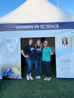 Charlotte Radiology staff photographed while posing in front of a banner that says Women in Science for a Leukemia & Lymphoma Society (LLS) event