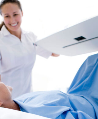 Technologist standing over a patient while holding an open MRI machine to help a patient with MRI claustrophobia