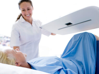 Technologist standing over a patient while holding an open MRI machine to help a patient with MRI claustrophobia